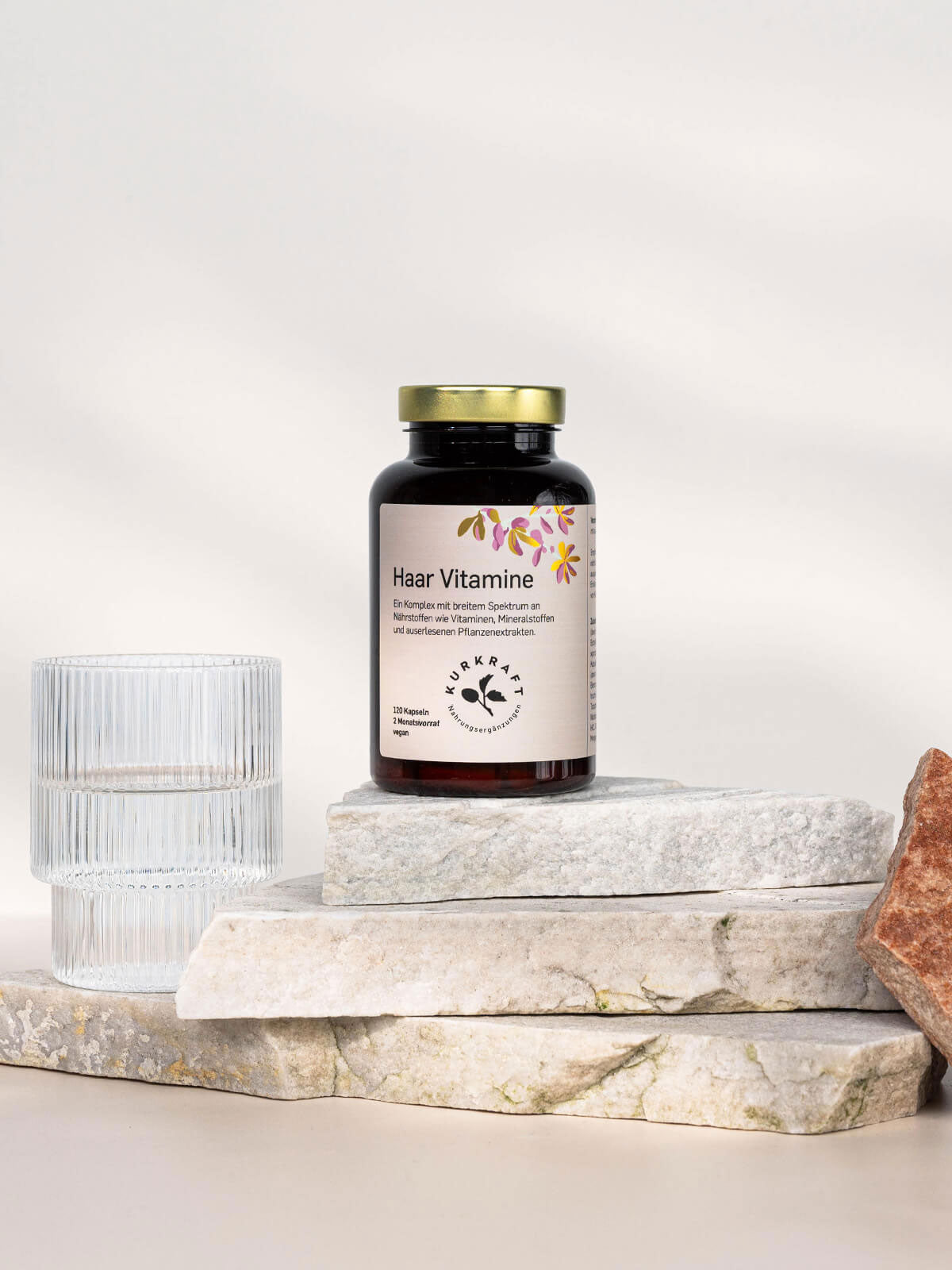 Haarvitamine im Glas auf Steinuntergrund mit Wasserglas – natürliche Nährstoffquelle für gesundes, kräftiges Haar