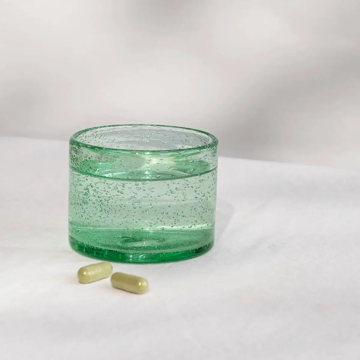 Geöffnete Bio Gerstengras Kapsel mit grünem Pulver, Anwendung im Smoothie